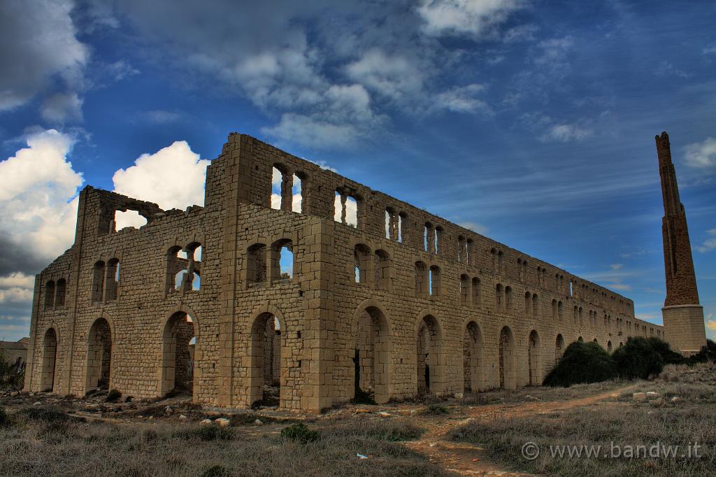 On_The_Road_019.jpg - Sampieri (RG) - Fornace Pisciotto - Splendido monumento d'archeologia industriale è la Fornace Penna, stabilimento che produceva laterizi utilizzando l'argilla estratta dalle cave vicine. Localmente è noto come "stabilimento bruciato" in ricordo dell'incendio che nel 1924 lo distrusse, ponendo fine all'attività produttiva avviata appena un decennio prima. La Fornace era stata costruita, infatti, nel 1912. I ruderi dell'ardita architettura con la ciminiera ancora alta, nonostante i recenti crolli, dominano il litorale di Sampietri, accogliente località balneare che conserva i segni dell'originario villaggio marinaro in alcune case di pescatori e nel molo, memoria dell'ottocentesco piccolo scalo di bastimenti destinati al commercio con Malta.